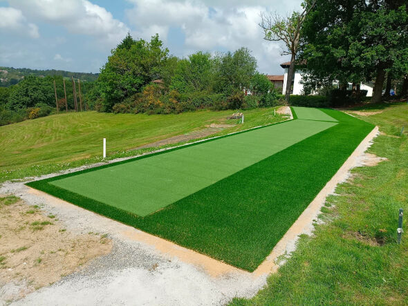 Edmonton Outdoor tee line consisting of one continuous green synthetic grass strip surrounded by trees